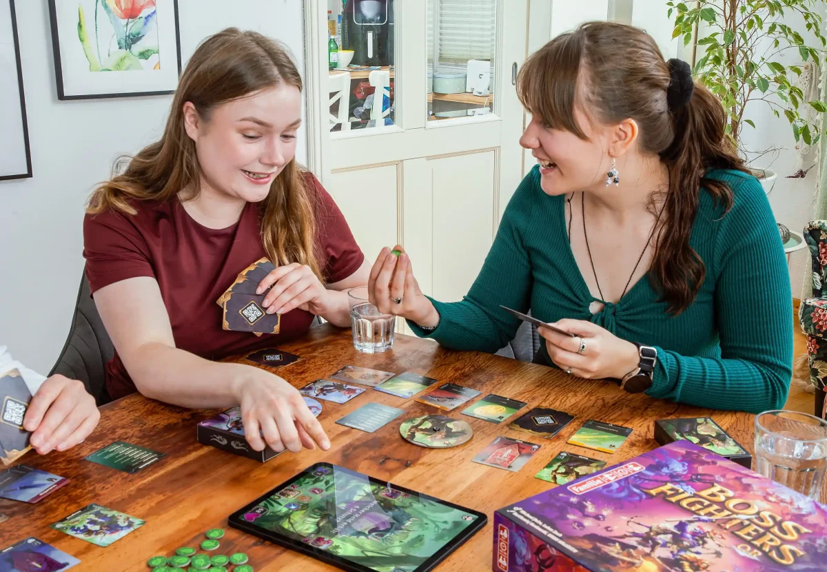 Zwei Frauen spielen das Brettspiel Boss Fighters QR