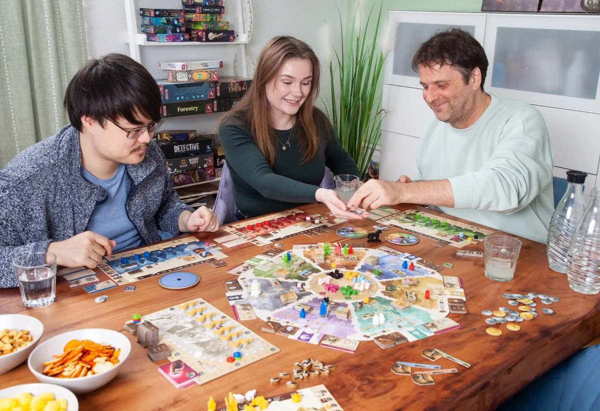 Spielgruppe beim Kennerspiel Medico gemeinsam an einem Tisch mit Spielbrett und Spielmaterial.